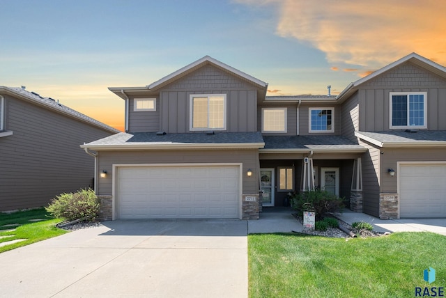 view of front facade with board and batten siding, stone siding, a garage, and driveway