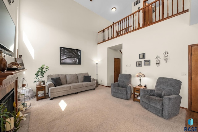 living room with a towering ceiling, carpet floors, a tiled fireplace, and baseboards