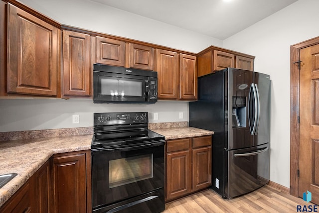kitchen featuring black appliances, light wood-style floors, light countertops, and brown cabinets