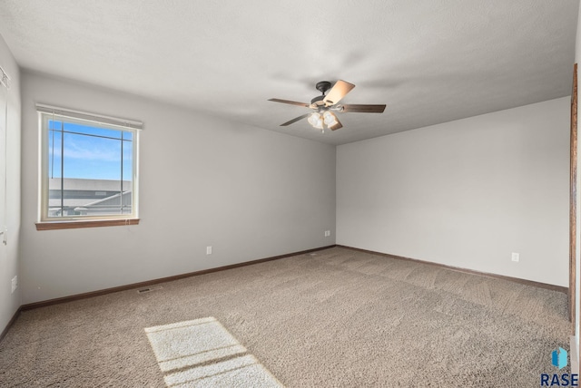carpeted empty room featuring ceiling fan and baseboards