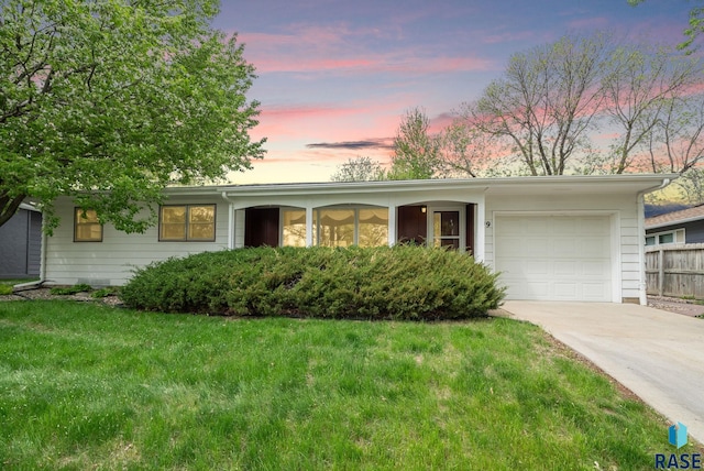 single story home with concrete driveway, an attached garage, and a lawn