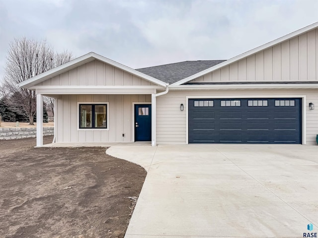 view of front facade with driveway, an attached garage, a shingled roof, and board and batten siding