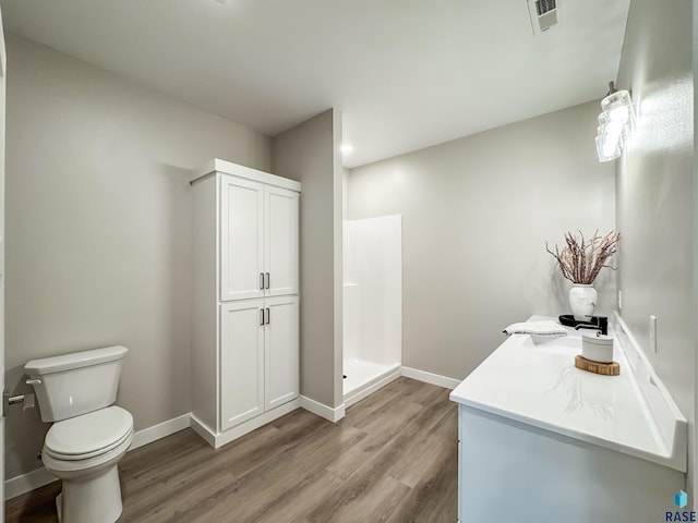 bathroom featuring wood finished floors, toilet, baseboards, and a shower