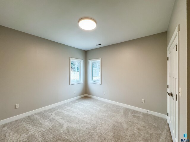 unfurnished room featuring baseboards and light colored carpet