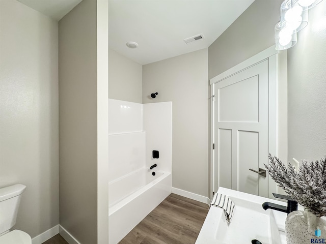 full bathroom featuring toilet, wood finished floors, baseboards,  shower combination, and vanity
