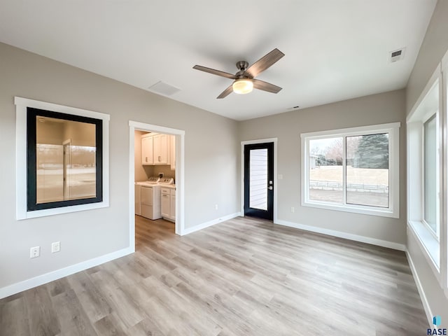 spare room with washing machine and dryer, a ceiling fan, light wood-type flooring, and baseboards