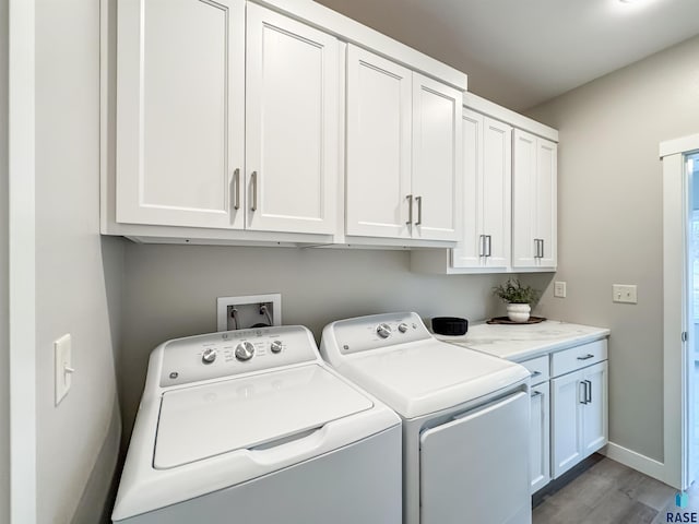 laundry area featuring cabinet space, separate washer and dryer, wood finished floors, and baseboards