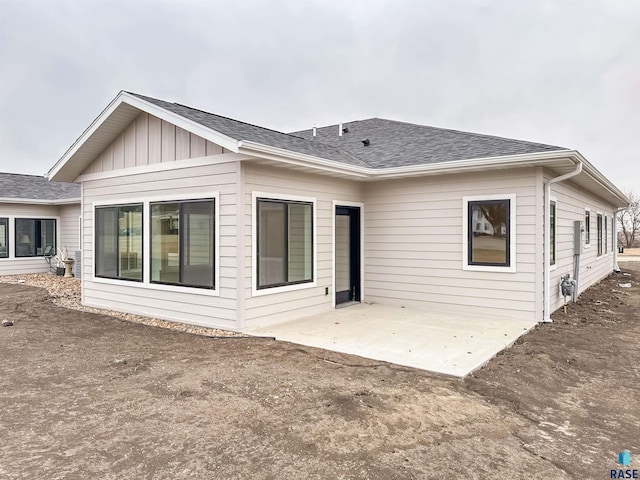 back of house featuring a patio area, a shingled roof, and board and batten siding