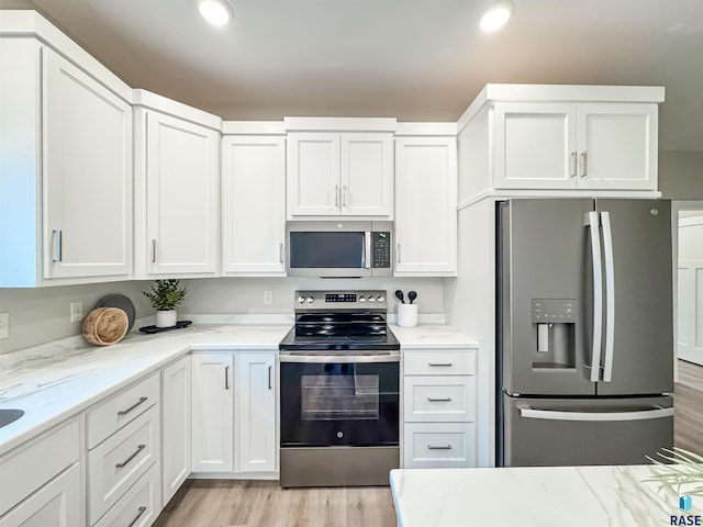 kitchen with appliances with stainless steel finishes, light wood-type flooring, white cabinets, and recessed lighting