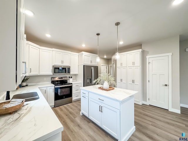 kitchen featuring stainless steel appliances, white cabinets, light stone countertops, light wood-style flooring, and recessed lighting