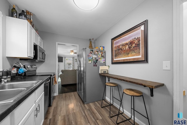 kitchen featuring stainless steel appliances, dark countertops, dark wood-style floors, and white cabinets