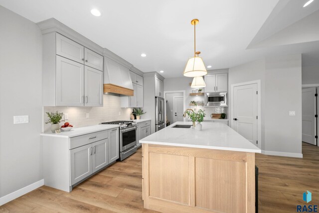 6609 E Corsair Dr, Sioux Falls, SD 57110 - kitchen with high quality appliances, gray cabinets, baseboards, tasteful backsplash, and custom exhaust hood