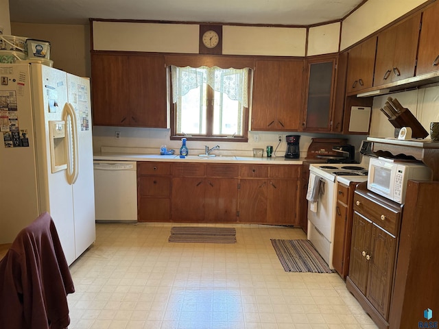 kitchen featuring white appliances, light countertops, light flooring, and a sink