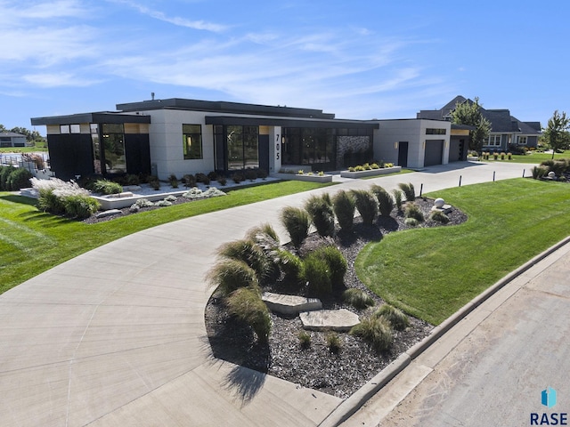 view of front facade featuring concrete driveway, an attached garage, and a front lawn