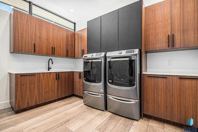 laundry area with cabinet space, separate washer and dryer, and light wood-type flooring