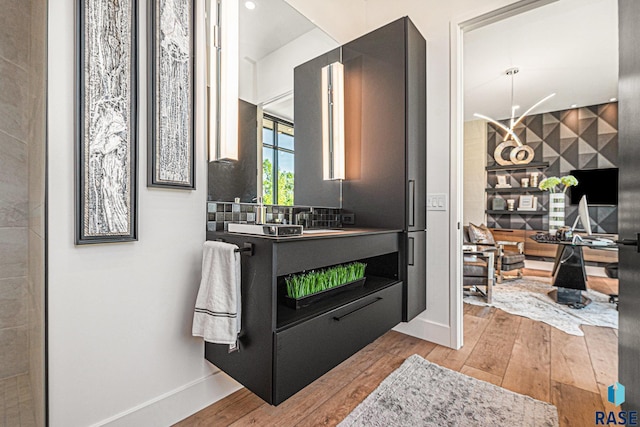 bathroom featuring wood-type flooring, baseboards, a sink, and recessed lighting