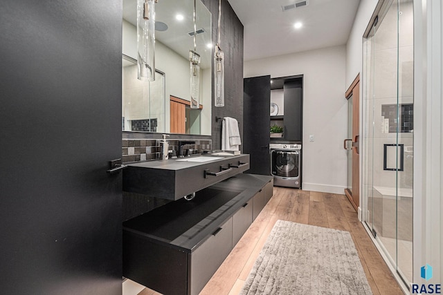 full bath with washer / dryer, tasteful backsplash, wood finished floors, a stall shower, and vanity