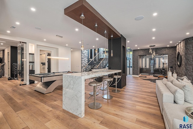 bar area featuring light wood-type flooring, stairway, pool table, recessed lighting, and refrigerator with ice dispenser