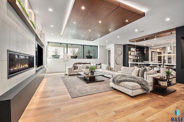 living area with light wood-type flooring, a tiled fireplace, and recessed lighting