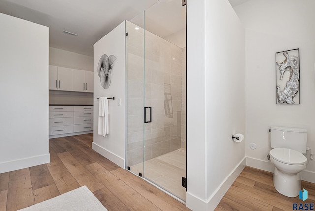 full bathroom featuring hardwood / wood-style flooring, a shower stall, toilet, and baseboards