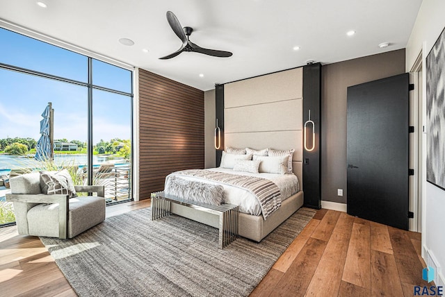 bedroom featuring hardwood / wood-style flooring, floor to ceiling windows, access to outside, recessed lighting, and a ceiling fan
