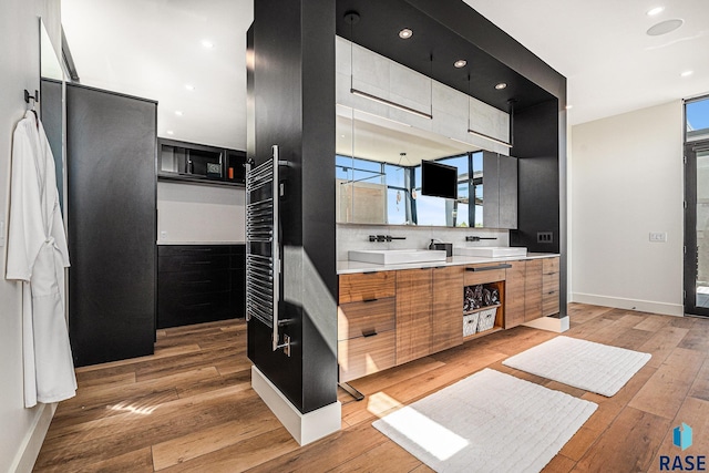 full bath with hardwood / wood-style floors, baseboards, vanity, recessed lighting, and a towel warming rack