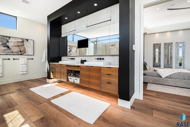 ensuite bathroom with wood-type flooring, baseboards, double vanity, and recessed lighting