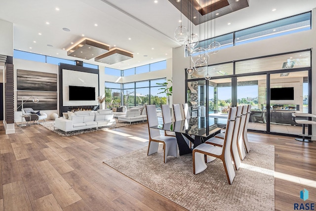 dining space with a high ceiling, wood finished floors, plenty of natural light, and recessed lighting