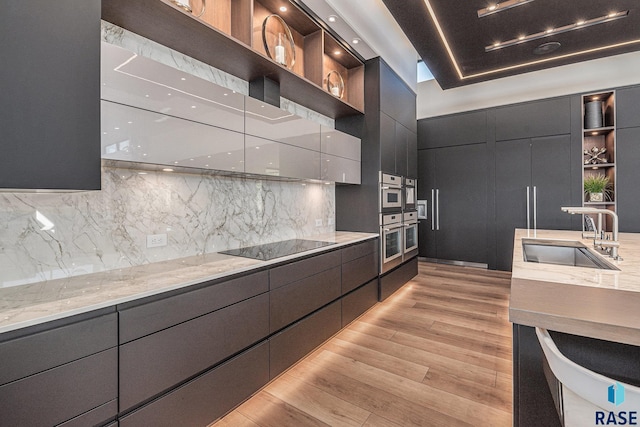kitchen with open shelves, modern cabinets, a sink, light wood finished floors, and black electric cooktop