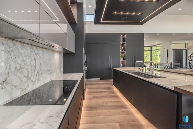 kitchen featuring modern cabinets, a sink, light wood-style flooring, exhaust hood, and recessed lighting