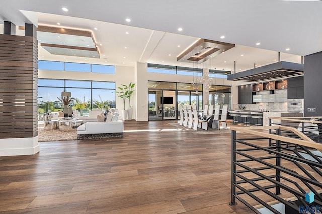 living room with recessed lighting, wood finished floors, plenty of natural light, and a raised ceiling