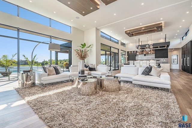 living room with a towering ceiling, light wood-style flooring, and recessed lighting