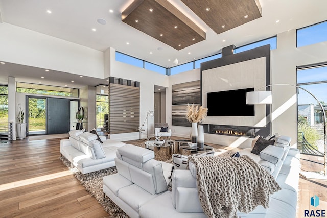 living area featuring a towering ceiling, recessed lighting, wood finished floors, and a high end fireplace
