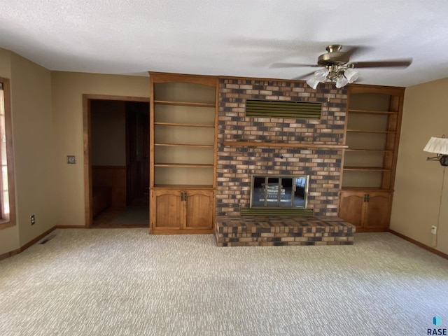 1208 Hampshire Cir, Luverne, MN 56156 - unfurnished living room featuring a fireplace, a ceiling fan, carpet flooring, baseboards, and built in shelves