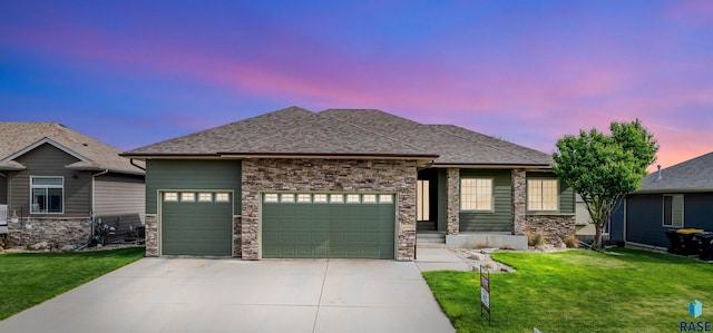 view of front of property featuring a garage, concrete driveway, a front yard, and stone siding