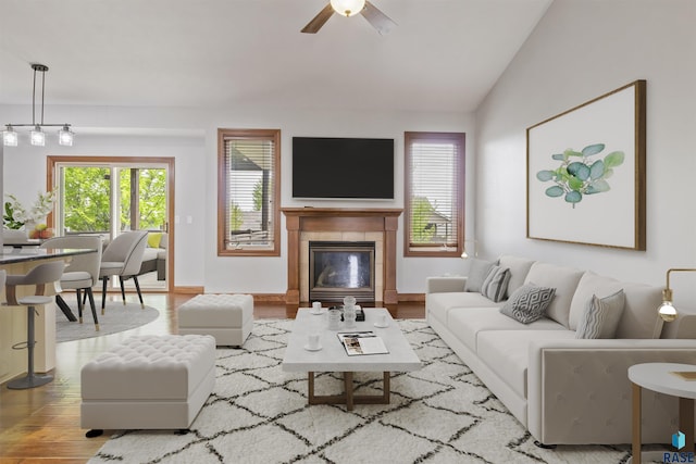 living area with wood finished floors, vaulted ceiling, ceiling fan, and a tiled fireplace