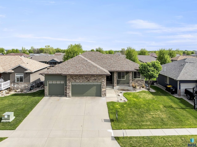 single story home featuring an attached garage, stone siding, concrete driveway, a front lawn, and a residential view