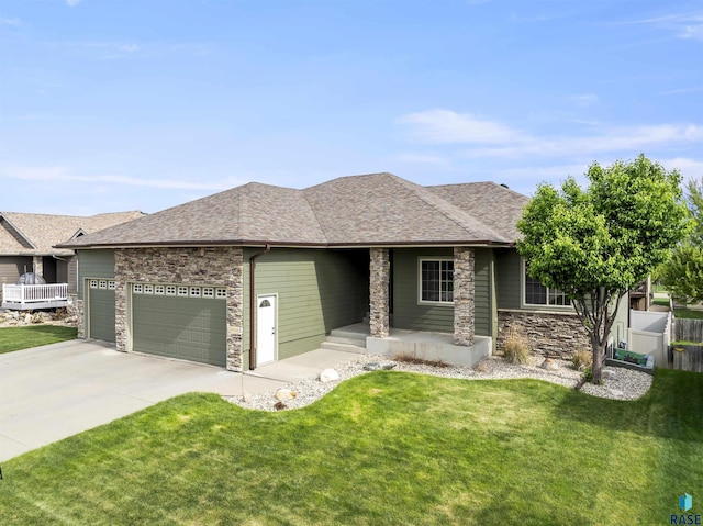 view of front facade with stone siding, an attached garage, a front yard, and driveway