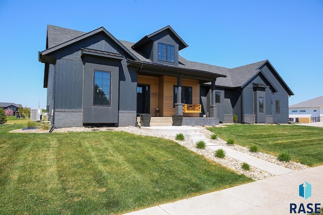 view of front of house with a porch, a front yard, and brick siding