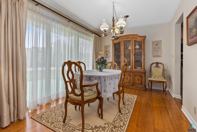 dining space with a chandelier, light wood finished floors, and baseboards