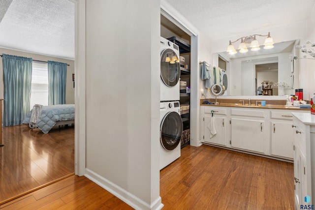 washroom with stacked washer and clothes dryer, wood finished floors, and a textured ceiling