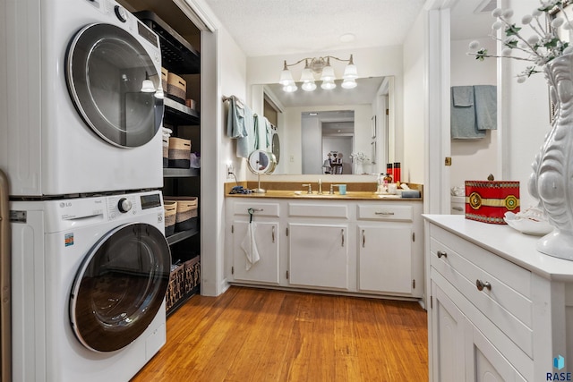 laundry area with stacked washing machine and dryer and light wood-style floors