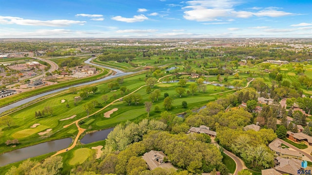 aerial view of property and surrounding area with a nearby body of water, a tree filled landscape, a local golf course, and nearby suburban area