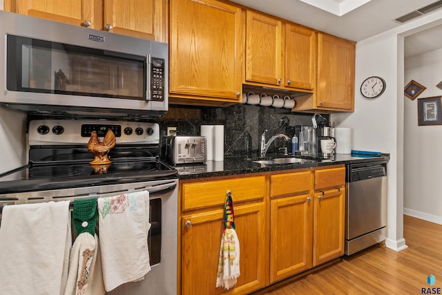 kitchen with stainless steel appliances, a sink, decorative backsplash, and baseboards