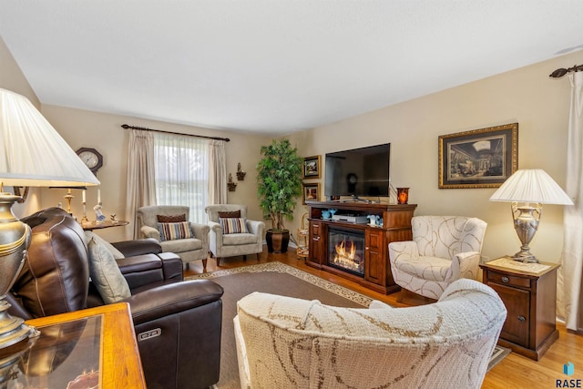 living room with light wood-type flooring and a glass covered fireplace