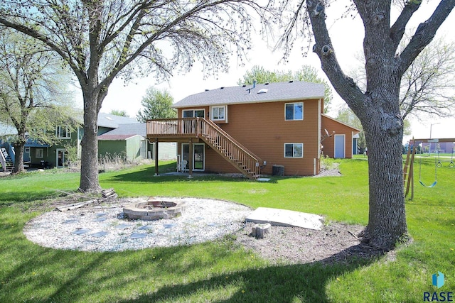 rear view of house featuring stairway, an outdoor fire pit, a wooden deck, and a lawn