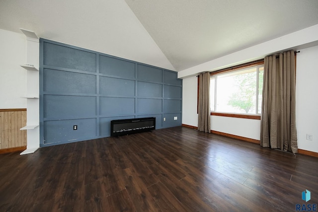 unfurnished living room featuring wood finished floors, lofted ceiling, a decorative wall, and baseboards