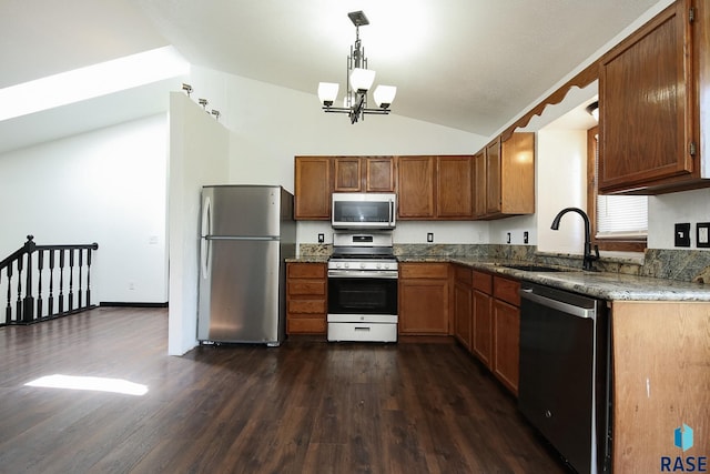kitchen with appliances with stainless steel finishes, a sink, lofted ceiling, brown cabinets, and a chandelier