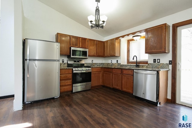 kitchen with stainless steel appliances, a chandelier, vaulted ceiling, dark wood-style floors, and brown cabinetry