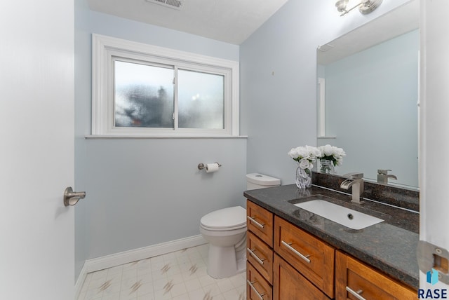 half bathroom with toilet, baseboards, and vanity